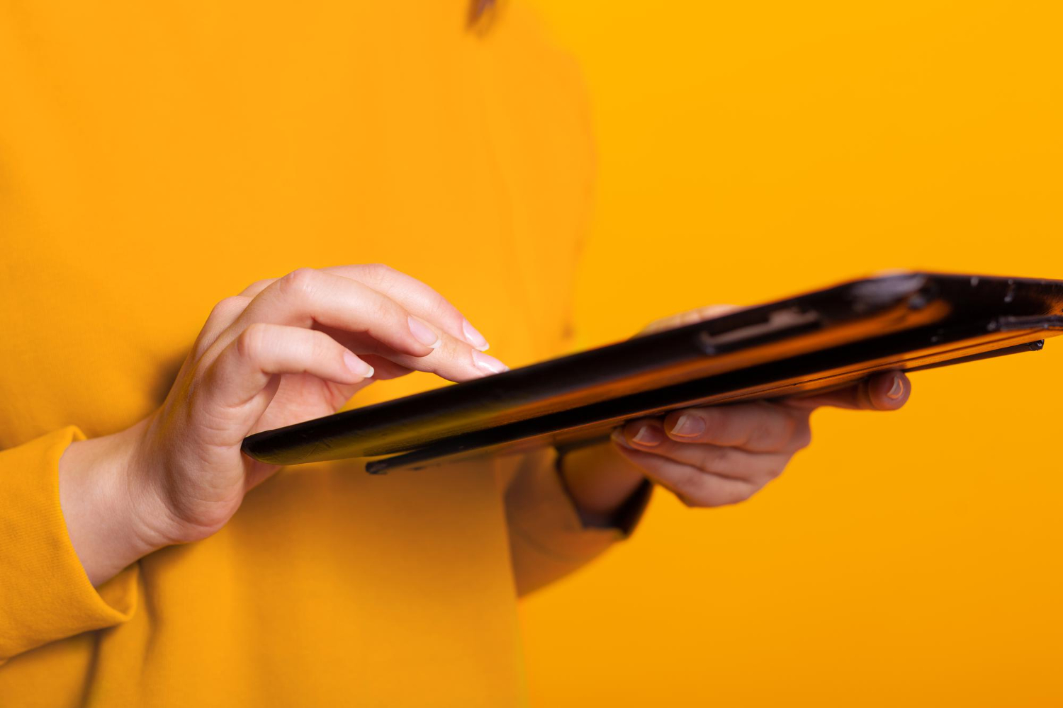 oranger Hintergrund, Frau tippt auf tablet für Krankentagegeldversicherung Vergleich.